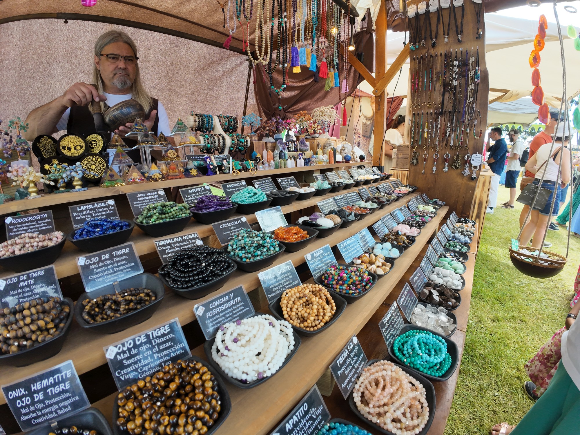 Vendor at a market stall selling crystal and gemstone bead jewelry and pendants Los Exconxuraos Festival medieval en Llanera