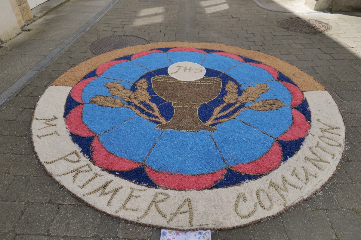 First Communion sidewalk flower display with a chalice and wheat, labeled “Mi Primera Comunión”